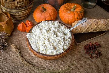 Beautiful rustic cottage cheese in a plate on the table, next to bread and pumpkins