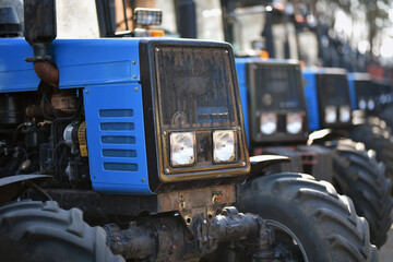 row of used identical tractors in second hand market