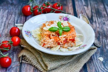 Home made italian oven baked tomato risotto  with a fresh leaf of basil and parmesan cheese 