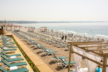The tourist season is open, very few tourists have arrived, there are many empty sunbeds and beach chairs. Konyaalti Beach, Antalya, Turkey.