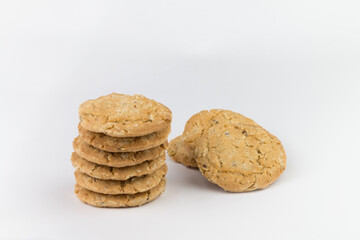 Cereal cookies are stacked on top of several pieces and have three pieces stacked on the back, and the cookies are brown and the image has a blank area next to the object and has a white background