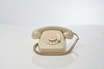 old telephone with dial on a reflective white background