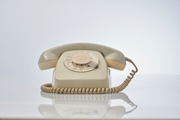 old telephone with dial on a reflective white background