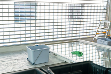 view of a large fold-down window and various cleaning supplies in a large and bright modern apartment room