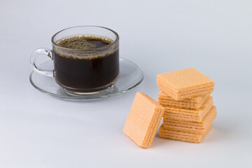 One cup of a coffee close-up on the back and several orange-flavoured wafers on top. The image has blank space beside the object and has a white background.
