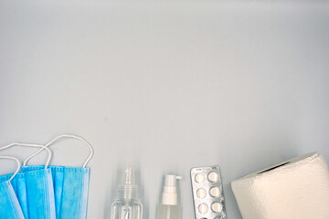 Surgical face mask, hand sanitizer, medicine pills and tissue rolls over white background