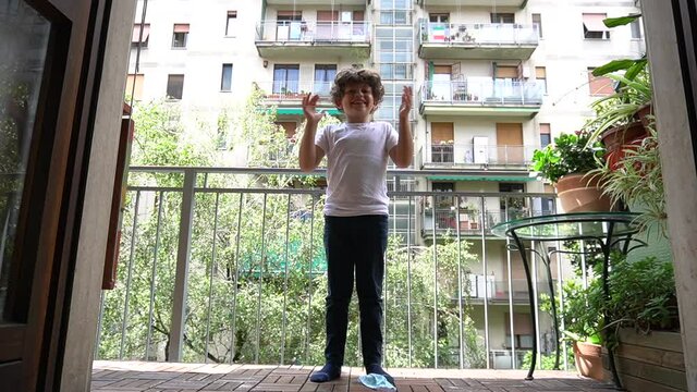 Europe, Italy , Milan - children boy  five years take off the mask , quarantine home due covid19 Coronavirus lockdown - life style in apartment - applaud the end of the epidemic , flash mob