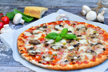  Close up of    hot italian pizza   classic ham. Fresh basil,tomato sauce ,mozzarella cheese , mushrooms and  minced meat .Concept poster for Restaurants or pizzerias. Top view