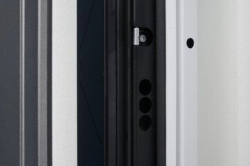 Glossy black metal entrance door with details: handle, open closed lock, hinges and threshold.