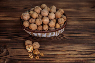 A basket full of inshell walnuts on a wooden background. Natural, healthy product. Space for text.