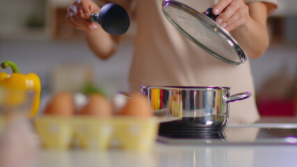 Unrecognizable woman cooking soup on kitchen. Housewife stirring soup with spoon