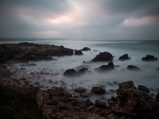 wallpaper of rocky beach landscape at sunset on a cloudy day