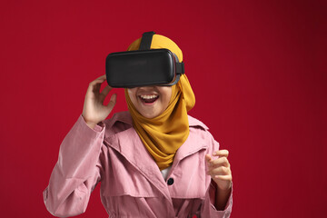 Happy young Asian muslim girl playing on VR glasses. Virtual reality concept, young girl having fun with headset goggles