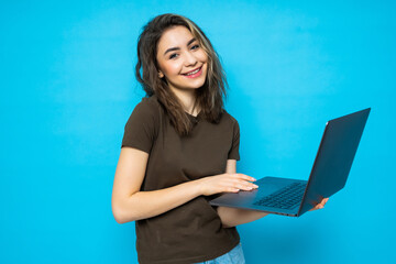 Portrait of a happy beautiful girl with laptop isolated over blue background