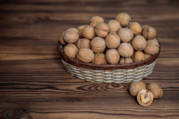 A basket full of inshell walnuts on a wooden background. Natural, healthy product. Space for text.