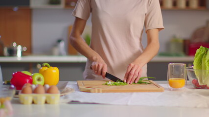 Obraz na płótnie Canvas Woman cutting onions on wooden board at kitchen. Housewife preparing salad