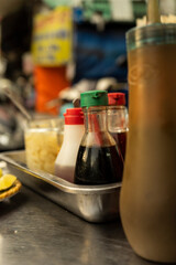 Traditional Vietnamese noodle condiment tray with dish of lemon slices, jar of chili, fish sauce, soy sauce, spoons and chopsticks at street food cart in Ho Chi Minh city, Vietnam