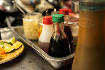 Traditional Vietnamese noodle condiment tray with dish of lemon slices, jar of chili, fish sauce, soy sauce, spoons and chopsticks at street food cart in Ho Chi Minh city, Vietnam