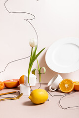 Floral and fruit composition with tulip, fruits, dishware isolated on beige