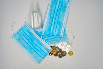 Surgical face mask, medicine pills and hand sanitizer over white background