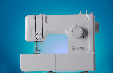 Modern sewing machine close-up on blue background
