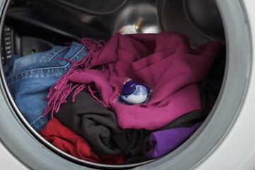 The capsule for washing lies in the drum of the washing machine on the laundry.