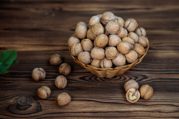 A basket full of inshell walnuts on a wooden background. Natural, healthy product. Space for text.