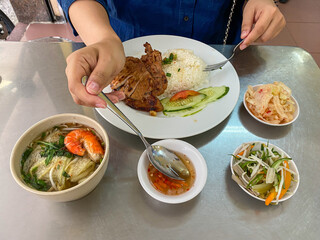 Woman eating Vietnamese pork chop rice with fish sauce