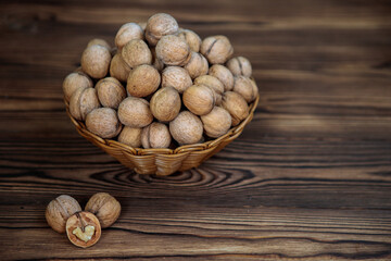 A basket full of inshell walnuts on a wooden background. Natural, healthy product. Space for text.
