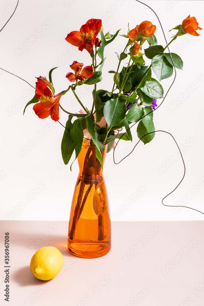 Poster floral composition with roses and red Alstroemeria in wires in orange vase near lemon isolated on white