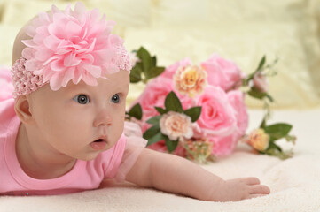 Cute little baby girl on bed with flowers