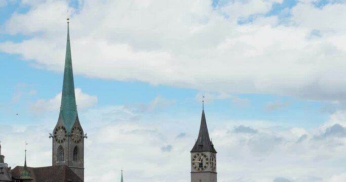 Clouds moving quickly behind two church clock bell towers in Zurich city Switzerland
