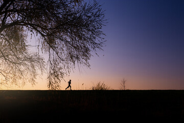 Boy or male man runs at sunset to stay healthy, healthy lifestyle, sport concept, calm and warm evening Landscape with blue and orange colors - 356968457