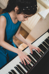 School age British Indian girl practices a piano at home. 