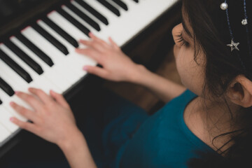 School age British Indian girl practices a piano at home. 