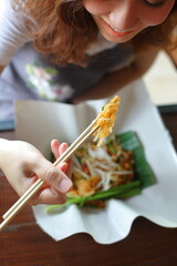 young woman eating a Thai style fried noodle