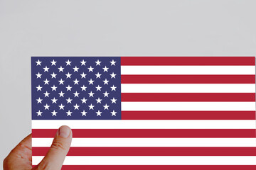 Male hand holding the American flag paper flag.
White background.National flag.