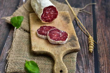 Italian  dried   artisan  pork salami,parmesan cheese ,peperoncino  and fresh basil on wooden background .Rustic  home made food