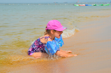 A happy child is swimming in the sea. Little girl on the beach in summer lifestyle. A fun pastime and active sportive leisure. Concept of happy childhood