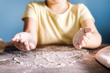child with floured hands on the kitchen table