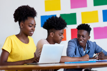 Learning african american female student at computer with group of students