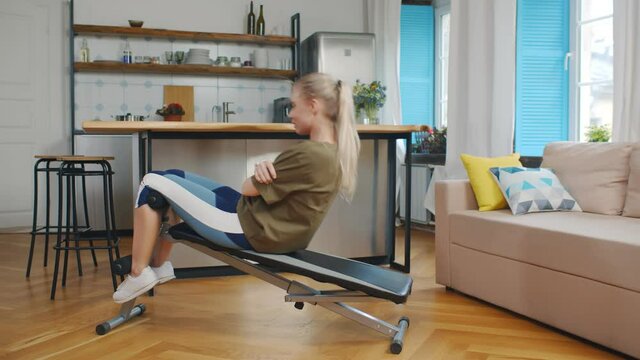 Side view of young woman doing work out on exercise bench at home