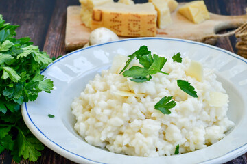 Italian creamy  cheese risotto with parmesan cheese and fresh basil on rustic background