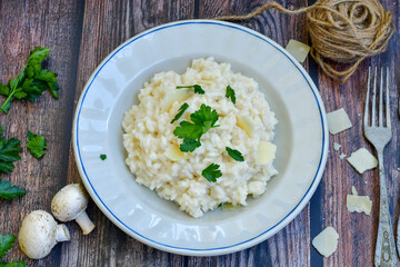 Italian creamy  cheese risotto with parmesan cheese and fresh basil on rustic background