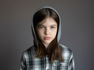 Portrait of a young serious girl in a hoodie on a dark background
