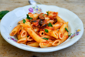 Home made italian penne pasta with tomato sauce and olives