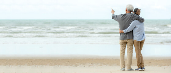 Asian Lifestyle senior couple hug and pointing on the beach happy in love romantic and relax...