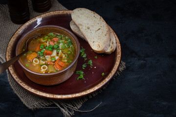 Vegan vegetable soup and bread in bowl on dark table