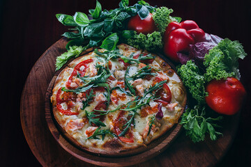 fresh Italian pizza, with tomatoes, caviar and arugula on a thin cake. The pizza rests on a wooden round board around decorated with vegetables 