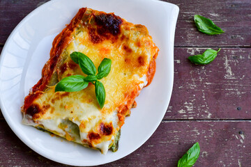   Delicious Home made Lasagna  with minced meat,tomato sauce and spinach  on a wooden rustic  background.Home made italian meal